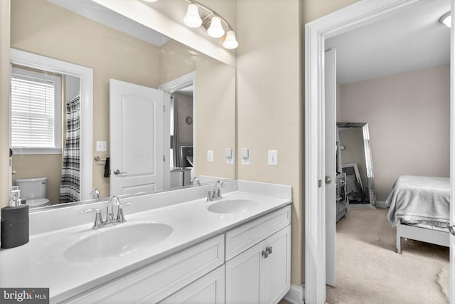 bathroom featuring ensuite bath, toilet, double vanity, and a sink