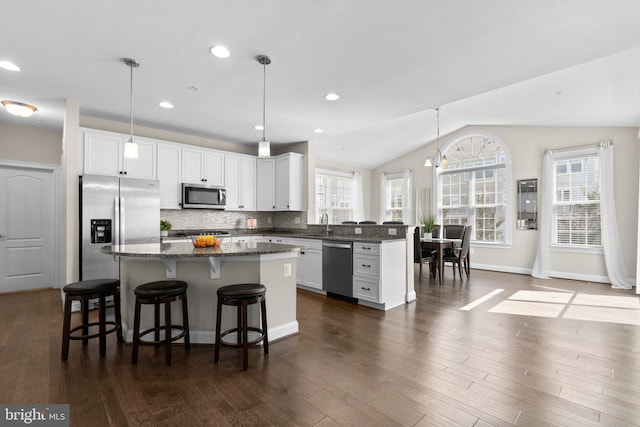 kitchen featuring a kitchen island, a kitchen bar, lofted ceiling, decorative backsplash, and stainless steel appliances