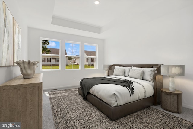 carpeted bedroom featuring recessed lighting, baseboards, a raised ceiling, and visible vents