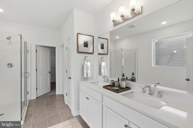 bathroom featuring tile patterned floors, a stall shower, double vanity, and a sink