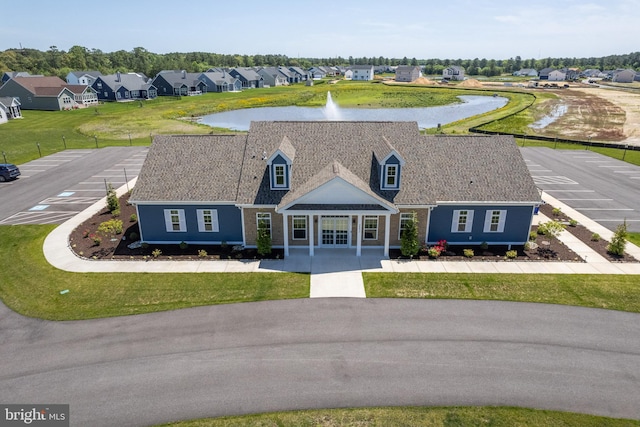 view of front of home with a residential view, a water view, roof with shingles, and uncovered parking