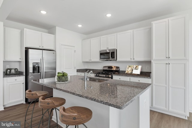 kitchen featuring a sink, wood finished floors, white cabinetry, and stainless steel appliances