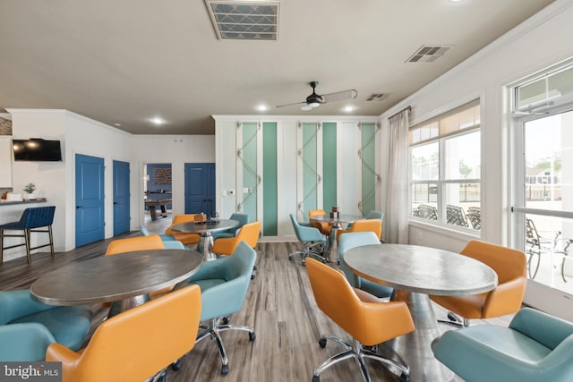 dining space with ceiling fan, wood finished floors, visible vents, and ornamental molding