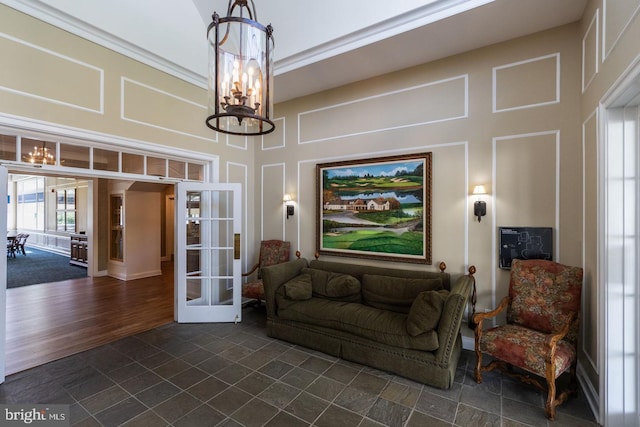 living area featuring french doors, a high ceiling, and an inviting chandelier