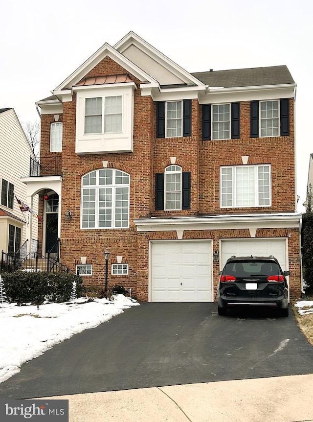 view of front of home featuring aphalt driveway, an attached garage, and brick siding