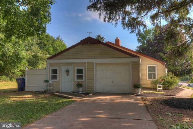 view of front of home featuring a front yard, concrete driveway, and a chimney