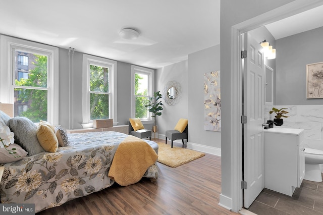 bedroom featuring a sink, baseboards, and wood finished floors