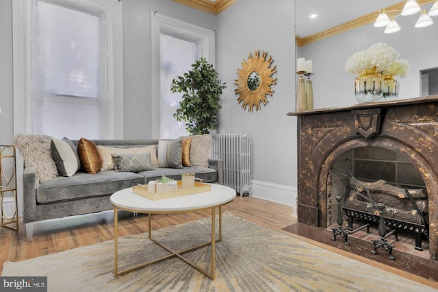 living room with crown molding, baseboards, a fireplace with flush hearth, radiator heating unit, and wood finished floors