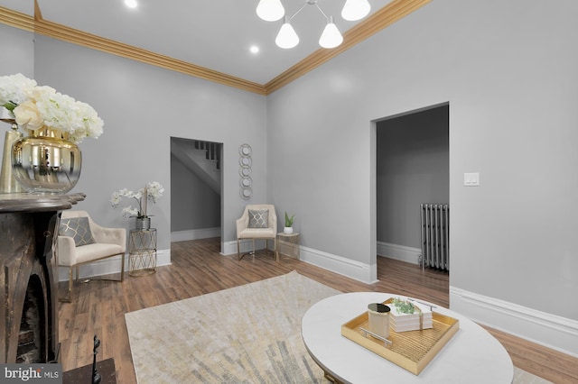 sitting room featuring crown molding, radiator heating unit, wood finished floors, and baseboards