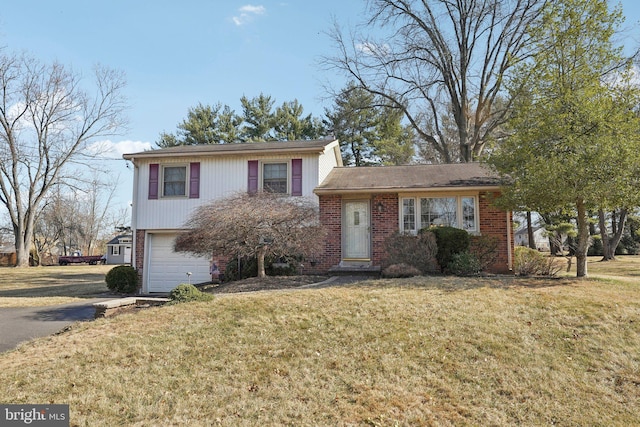 split level home with a garage, driveway, brick siding, and a front yard