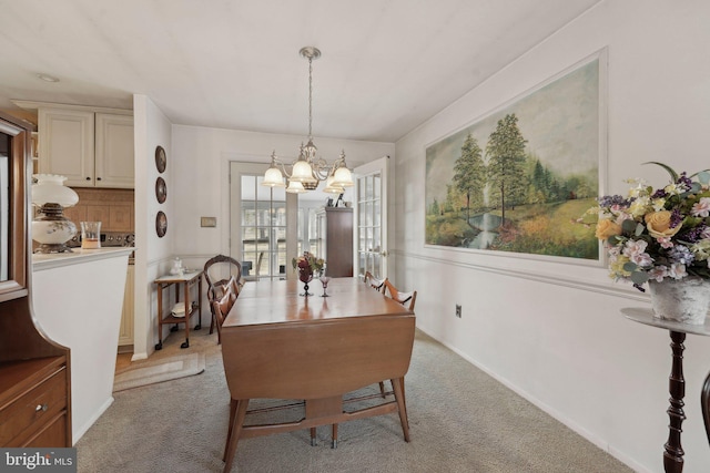 dining space with baseboards, light carpet, and a chandelier