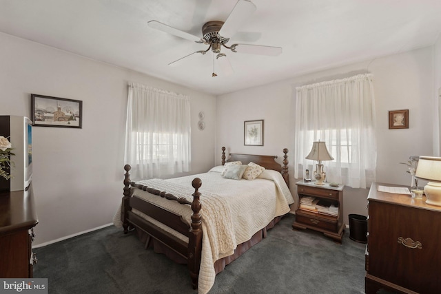 bedroom featuring multiple windows, baseboards, dark carpet, and ceiling fan