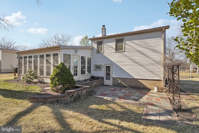 back of house featuring a patio, a yard, a sunroom, and a chimney