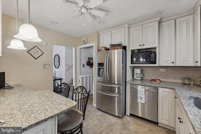 kitchen with decorative backsplash, decorative light fixtures, light stone counters, and appliances with stainless steel finishes