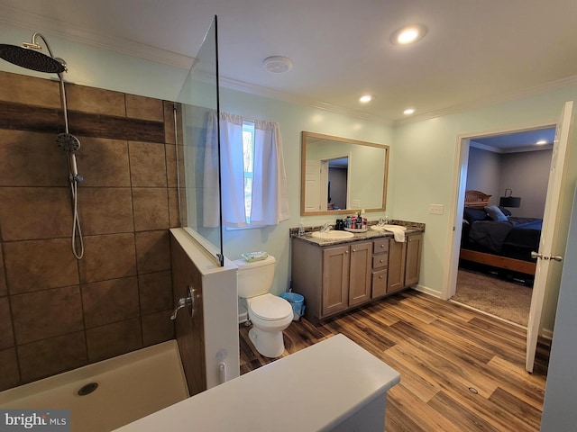 ensuite bathroom with crown molding, toilet, tiled shower, wood finished floors, and vanity