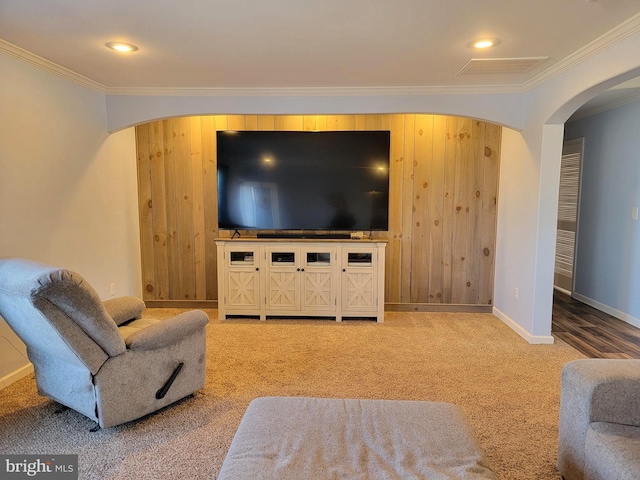 living room with baseboards, arched walkways, wood walls, crown molding, and light colored carpet