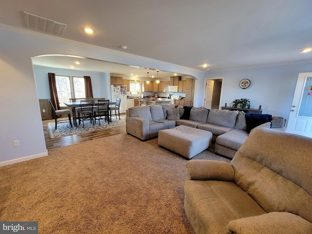 living room featuring recessed lighting, visible vents, arched walkways, and crown molding