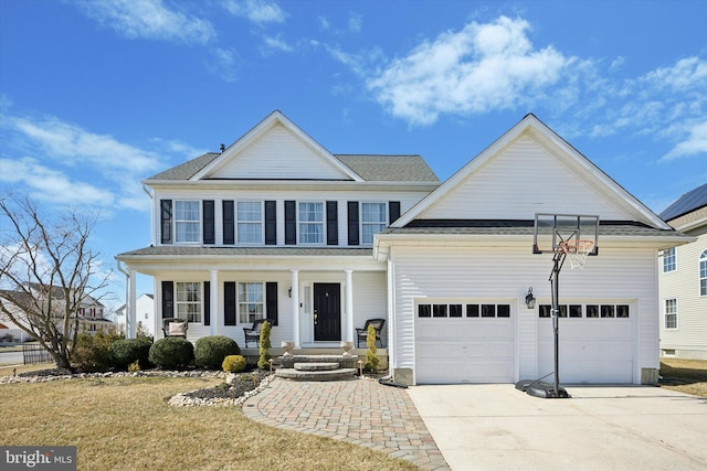 view of front of home with concrete driveway, a garage, covered porch, and roof with shingles