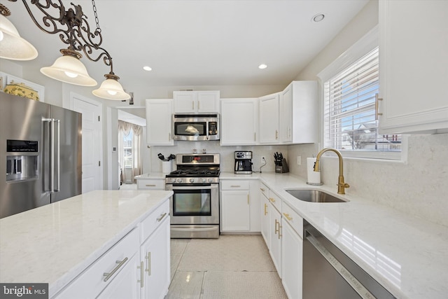 kitchen with a sink, light stone counters, tasteful backsplash, appliances with stainless steel finishes, and white cabinets