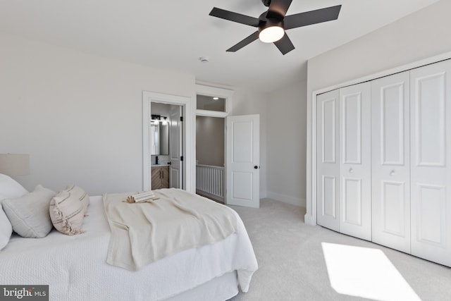 bedroom with connected bathroom, baseboards, ceiling fan, light colored carpet, and a closet