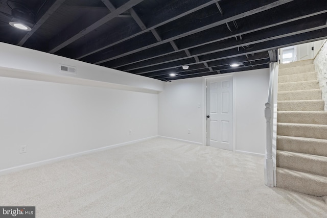 finished below grade area featuring stairway, carpet flooring, visible vents, and baseboards