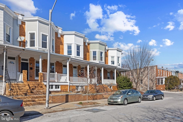 townhome / multi-family property featuring a residential view, brick siding, and a porch