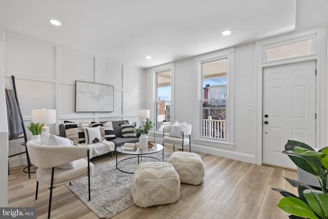 living room featuring a decorative wall, recessed lighting, and light wood-type flooring