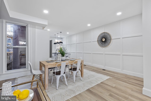 dining area with recessed lighting, light wood-style floors, and a decorative wall