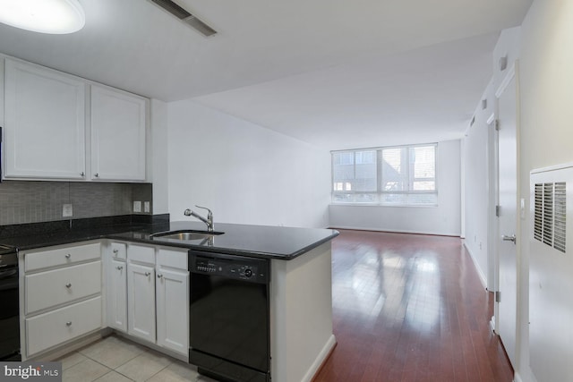 kitchen featuring visible vents, a peninsula, a sink, white cabinets, and dishwasher