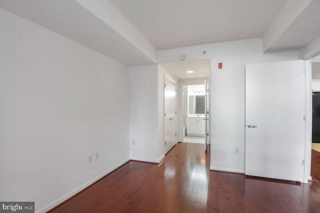 interior space with refrigerator, ensuite bath, baseboards, and wood finished floors