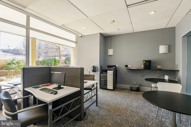 carpeted office with a drop ceiling and baseboards