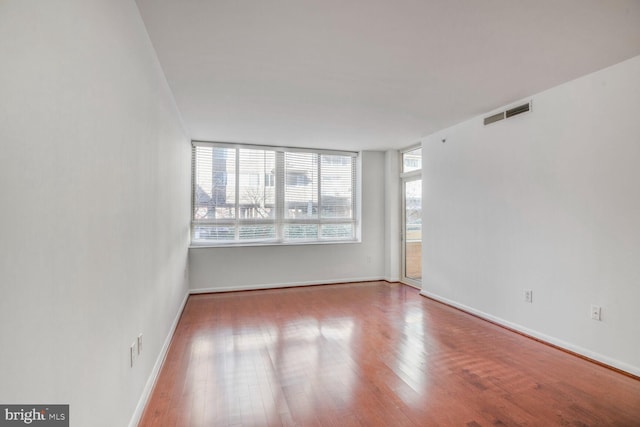 spare room featuring visible vents, baseboards, and wood finished floors