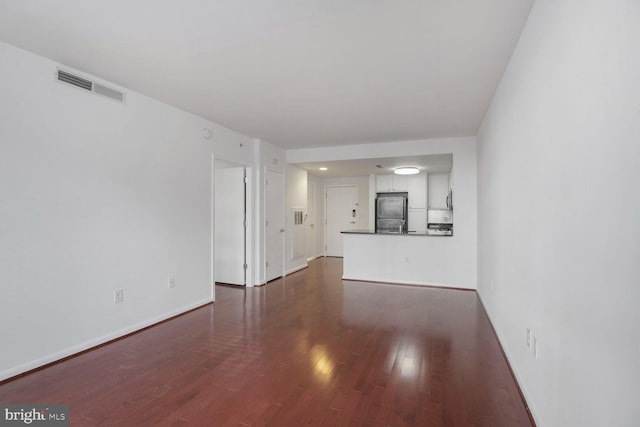 unfurnished living room featuring dark wood-style floors, visible vents, and baseboards