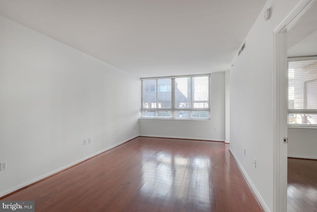 unfurnished room with visible vents, wood finished floors, and baseboards