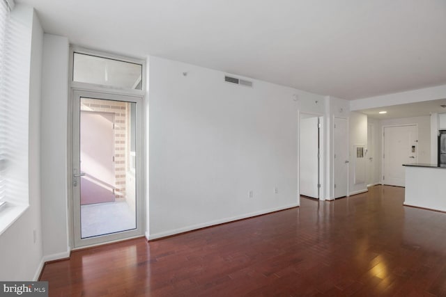 unfurnished living room featuring visible vents, baseboards, and wood finished floors