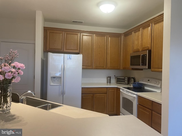 kitchen featuring white appliances, visible vents, a sink, light countertops, and brown cabinets