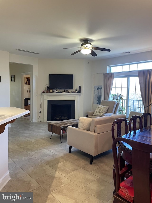 living area with light tile patterned floors, a fireplace, visible vents, and ceiling fan