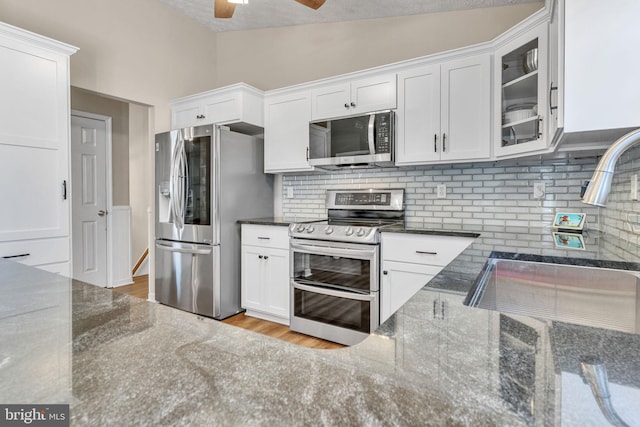 kitchen featuring white cabinets, appliances with stainless steel finishes, and dark stone counters