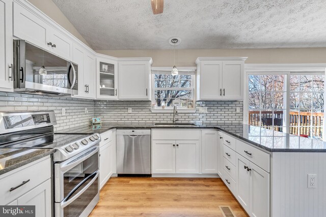 kitchen featuring visible vents, a sink, white cabinetry, appliances with stainless steel finishes, and a peninsula