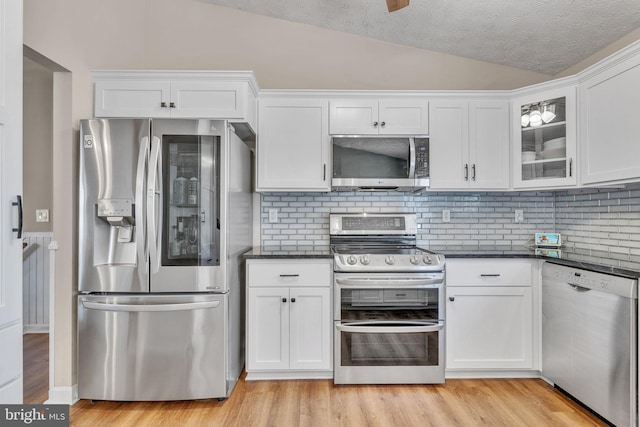 kitchen with white cabinets, stainless steel appliances, light wood-style floors, and lofted ceiling