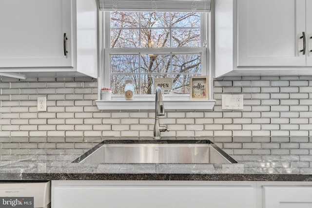 details featuring a sink, decorative backsplash, dishwashing machine, and white cabinetry