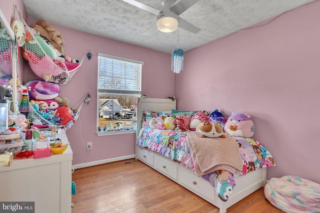 bedroom with a textured ceiling, a ceiling fan, baseboards, and wood finished floors