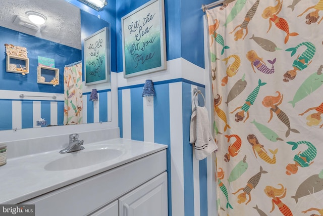 full bathroom with a textured ceiling, vanity, and a shower with curtain