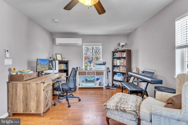 office area with a ceiling fan, a wall unit AC, plenty of natural light, and wood finished floors