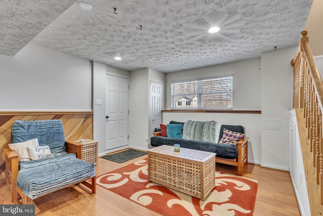 living area featuring a textured ceiling, baseboards, and wood finished floors