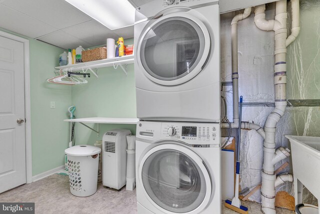 laundry room featuring tile patterned flooring, laundry area, and stacked washing maching and dryer