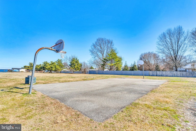 view of basketball court with a yard, community basketball court, and fence