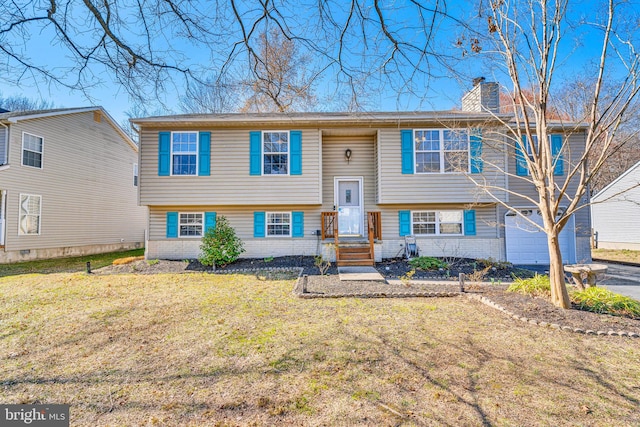 raised ranch featuring brick siding, a chimney, aphalt driveway, and a front lawn