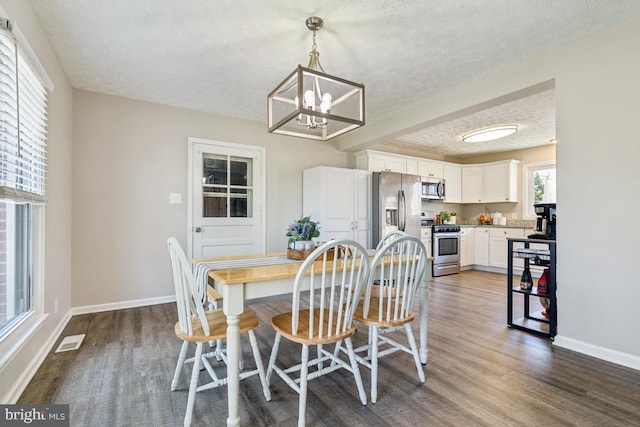 dining room featuring baseboards, visible vents, an inviting chandelier, dark wood-style flooring, and a textured ceiling