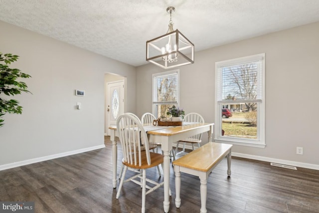 dining area with dark wood-style floors, baseboards, visible vents, and a textured ceiling